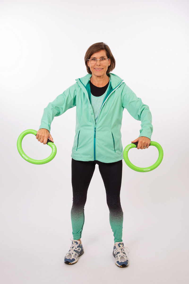Margitta hällt in beiden Hand jeweils einen grünen Smovey-Trainingsring, der nach unten zeigt